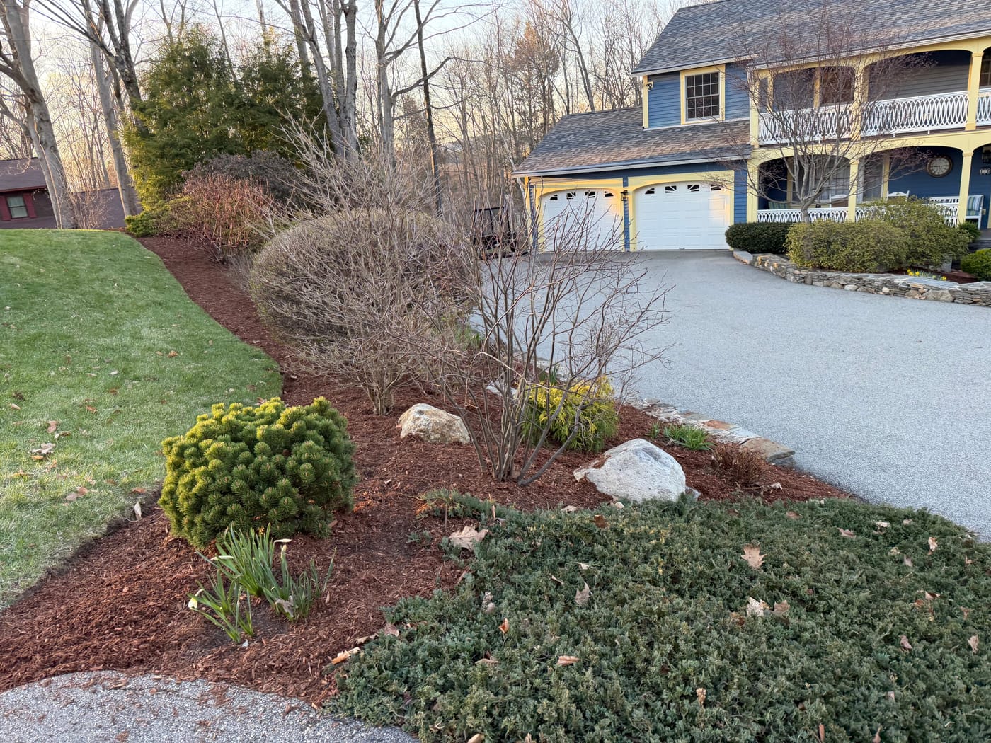 A tidy, freshly mulched landscape bed and lawn along a home's driveway in Keene, NH